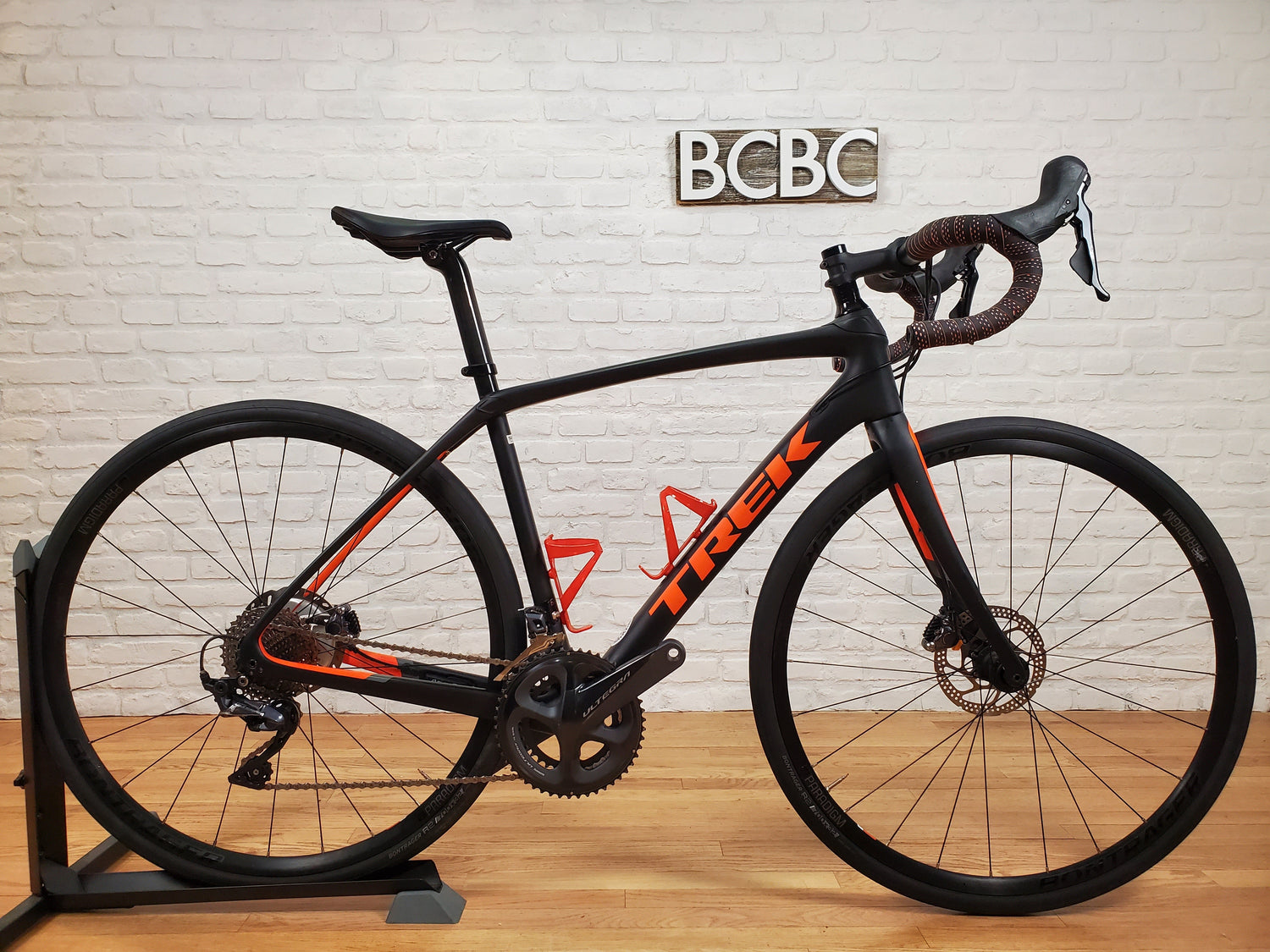 A collection of pre-owned Trek road bikes, including Emonda, Domane, and Madone models, displayed in a professional bike shop setting.